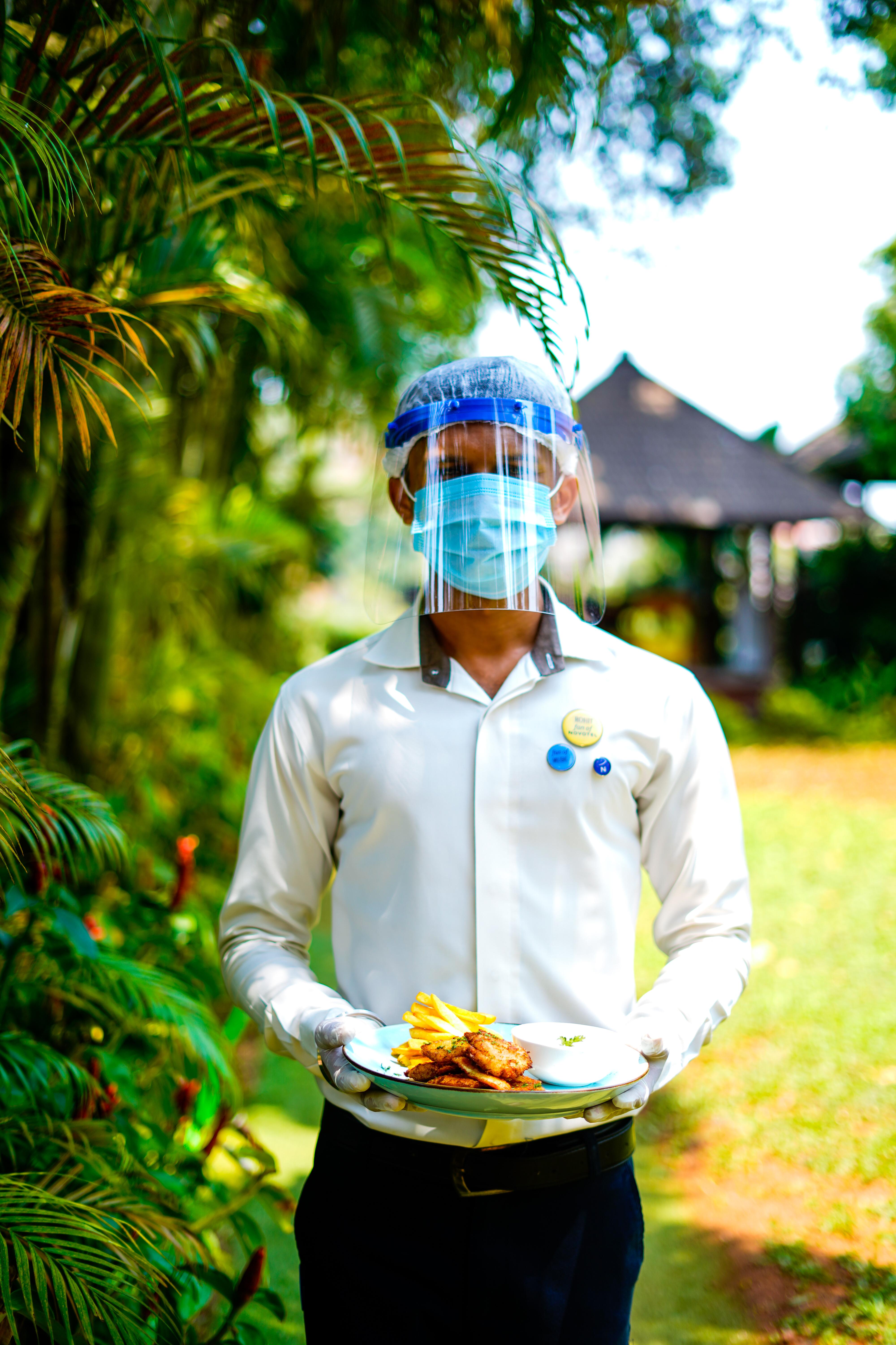 Novotel Goa Resort & Spa Candolim Esterno foto A hotel employee wearing a face shield and a face mask